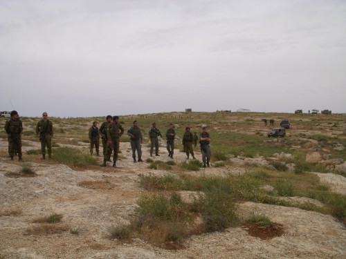 Soldiers standing with the illegal outpost in the background